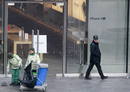 Un polic&iacute;a observa a trabajadores que limpian en el exterior de una tienda Apple despu&eacute;s de los incidentes provocados por un grupo de personas que hac&iacute;a cola comprar el nuevo iPhone 4S