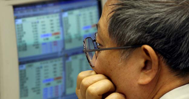 Un inversionista chino trabaja frente a un ordenador con las transacciones del d&iacute;a, en la bolsa de valores de Hong Kong (China).
