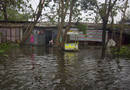 A boy stands in ankle-deep water outside a row of shacks in Yangon