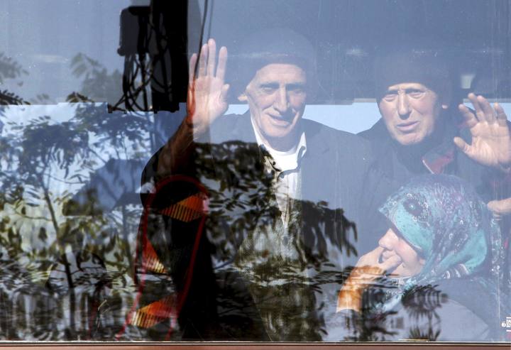 Albaneses saludan desde un autobus a punto de partir desde Serbia hacia la Uni&oacute;n Europea en la frontera de Presevo.