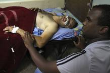 An Iraqi man sits near his relative, wounded in one of Thursday's bomb attacks, at a hospital in Sadr City, northeastern Baghdad