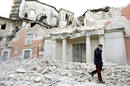 An Italian military carabinieri walks on debris past destroyed buildings after an earthquake, in downtown Aquila