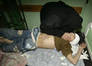Palestinian woman leans over her son at hospital in Gaza