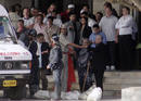 Guests stranded inside Taj Mahal Hotel stand at the entrance while waiting to be brought out of the hotel in Mumbai