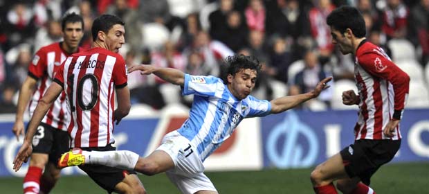 El delantero del M&aacute;laga Seba Fern&aacute;ndez (c) cae ante &Oacute;scar de Marcos (i) y Markel Susaeta.