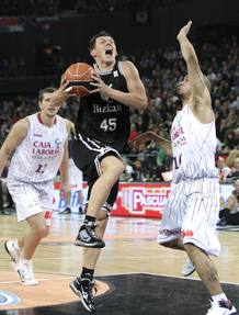 El base lituano del Bizkaia Bilbao Basket, Janis Blums (c), entra a canasta ante la oposici&oacute;n del escolta del Caja Laboral polaco, David Logan