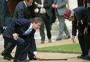 Cameron se agacha a por un bast&oacute;n que ha resbalado de las manos de uno de los veteranos, durante el homenaje a las combatientes de los nazis de la segunda guerra mundial.