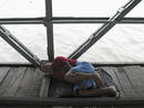 A boy takes a nap on a damaged wharf at a port on a swollen river in Yangon