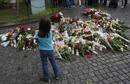 A child looks at flowers and candles that were placed on the market square outside the Oslo cathedral, to mourn the victims of a bomb blast and a rampage