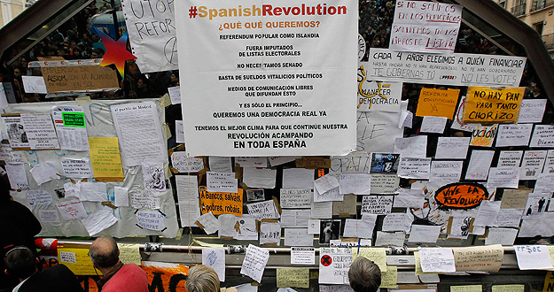 People look at signs put up by demonstrators in Madrid's Puerta del Sol