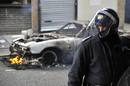 Un antidistubios se pone delante de un coche en llamas en el tecer d&iacute;a consecutivo de protestas.