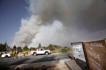 Una columna de humo asoma sobre el pueblo de Adeje mientras los efectivos de guardas forestales del Parque del Teide se movilizan para intentar controlar las llamas.