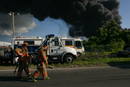 El cuerpo de Bomberos trabaja mientras se levanta una columna de humo debido al incendio de varios tanques de la refiner&iacute;a de petr&oacute;leo de la empresa Caribbean Petroleum Corporation