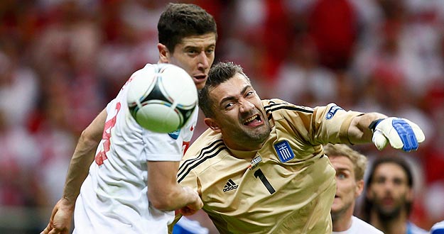 El delantero polaco Robert Lewandowski (L) intenta marcar al meta griego Kostas Chalkias en el primer partido del Grupo A de la Eurocopa 2012.