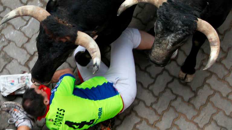 Dos corredores de verde a punto de ser embestidos por los toros de Miura