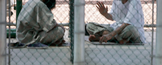 Dos hombres detenidos en el Campo VI de la prisión de Guantánamo en septiembre de 2007 conversan sentados en el suelo. Dos hombres detenidos en el Campo VI de la prisión de Guantánamo en septiembre de 2007 conversan sentados en el suelo.