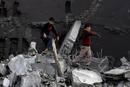 Dos ni&ntilde;os caminan sobre los escombros de un edificio destruido en un ataque a&eacute;reo israel&iacute; en el campo de refugiados de Shati, en la Franja de Gaza.