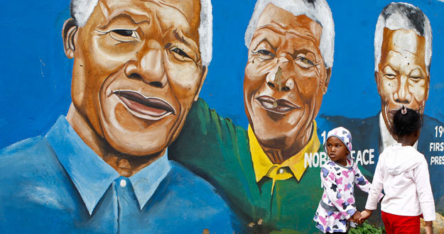 Dos ni&ntilde;as pasean junto a un grafiti del ex presidente de Sud&aacute;frica Nelson Mandela en Soweto.