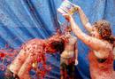 Un joven es rociado con tomate durante el festejo de Bu&ntilde;ol, para el que se ha precisado la utilizaci&oacute;n de seis camiones para transportar estas hortalizas.