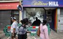 Personas observan los da&ntilde;os provocados en el escaparate de un comercio en Tottenham.