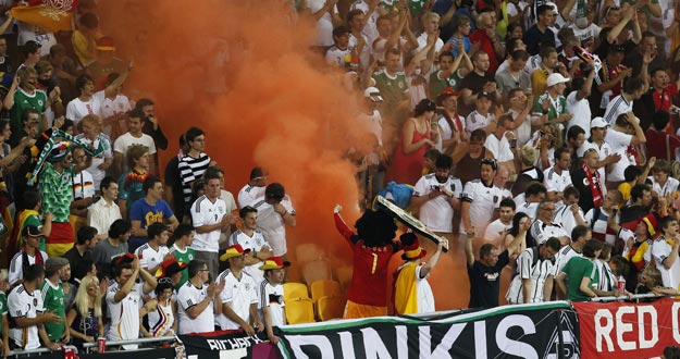 Fan&aacute;ticos alemanes usan una columna de humo en la tribuna para animar a su equipo ante Dinamarca