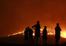 Residents watch a forest fire in the Anthousa suburb of Athens