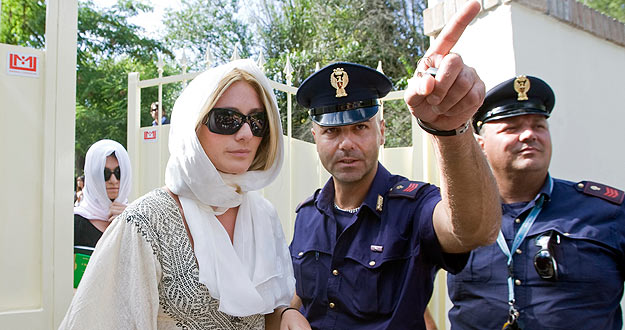 Una de las agasajadas por Gaddafi, es escoltada por los polic&iacute;as.