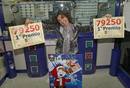 Elena de la C&aacute;mara, propietaria de la administraci&oacute;n de loter&iacute;a de la estaci&oacute;n de Chamart&iacute;n, en Madrid, muestra carteles con el Gordo del sorteo extraordinario de Navidad, del que vendi&oacute; una serie, tres millones de euros.