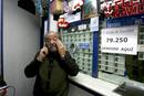 El propietario de la administraci&oacute;n de loter&iacute;a de la calle General Mill&aacute;n Astray de Madrid, con el cartel que anuncia que ha vendido el Gordo del sorteo extraordinario de Navidad, dotado con tres millones de euros a la serie.