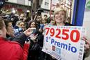 Yolanda Delgado, esposa del responsable de la administraci&oacute;n 22 de Zaragoza, ante numerosos periodistas con un cartel con el n&uacute;mero 79.250, premiado con el Gordo del sorteo extraordinario de la loter&iacute;a de Navidad.
