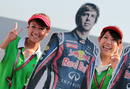 Dos azafatas posan junto a la imagen del piloto alem&aacute;n de Red Bull Sebastian Vettel