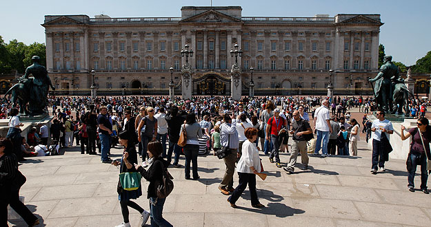 Tourists stand in front of Buckingham Palace in London