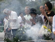 Un grupo de personas ora delante del cenotafio por las víctimas de la bomba atómica de Hiroshima este lunes, en el Domo de la Bomba Atómica en el Parque Monumento de Paz en Hiroshima (Japón).
