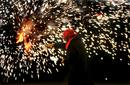 Un ciudadano baila y juega con fuego alrededor de una hoguera de San Juan instalada en el barrio de Sants de Barcelona, una de las miles que esta noche se encienden en toda Catalu&ntilde;a en conmemoraci&oacute;n del solsticio de verano.