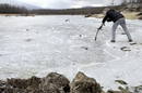 Un hombre intenta romper la gruesa capa de hielo que cubre el pantano del Pont&oacute;n Alto en Segovia