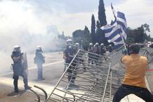 Un hombre ondea una bandera griega ante la Polic&iacute;a antidisturbios