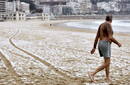 Un hombre se mete en el mar en la playa de La Concha en San Sebasti&aacute;n a pesar de la nieve
