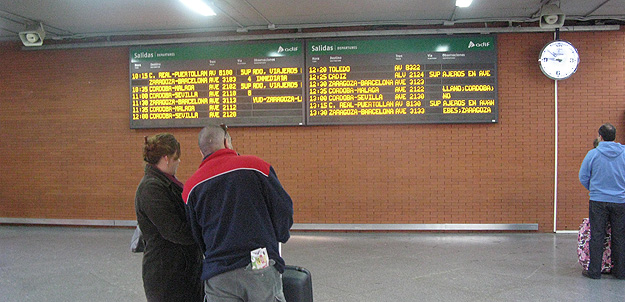 Javier y Mar comprueban en el panel de informaci&oacute;n de Atocha si su tren a M&aacute;laga est&aacute; afectado por la huelga.