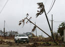 Cars drive under half-uprooted lightposts in Puerto San Carlos, Mexicos state of Baja California