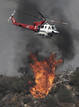 Un helic&oacute;ptero de los bomberos lucha por extinguir el fuego, que cerca Los &Aacute;ngeles.