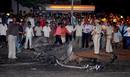Varias personas observan los restos de un coche tras la serie de explosiones y tiroteos dirigidos contra una estaci&oacute;n de trenes y dos hoteles de lujo, el Oberoi y el Taj Mahal.
