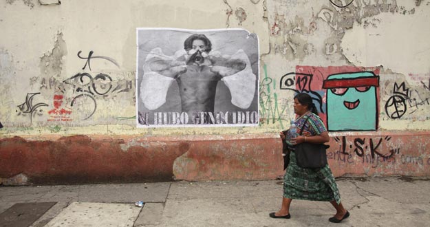 Una mujer indígena camina delante de un cartel en el que se puede leer "sí hubo genocidio"