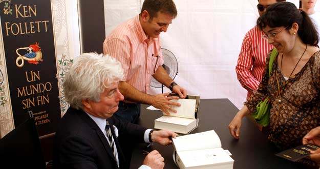 El escritor gal&eacute;s Ken Follet firma un ejemplar de su &uacute;ltima novela, "Un mundo sin fin", a una lectora durante la firma de libros que ha realizado en la Feria del Libro de Madrid.