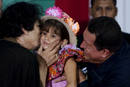 Libyas leader Gaddafi kisses a girl held by Venezuelas President Chavez during ceremony in Margarita Island