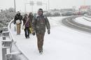 Usuarios de autobuses detenidos a causa de la nieve tratan de alcanzar una estaci&oacute;n de metro junto a la M-40 de Madrid.