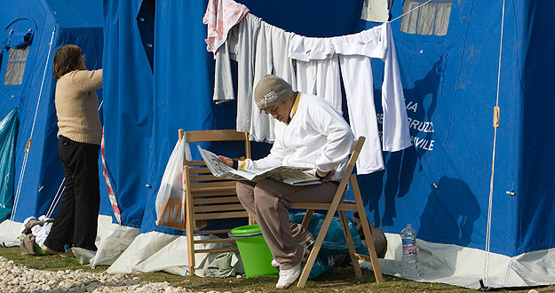 Un hombre lee el periódico junto a una tienda de campaña del campo de desplazados de L'Aquila. Un hombre lee el periódico junto a una tienda de campaña del campo de desplazados de L'Aquila.