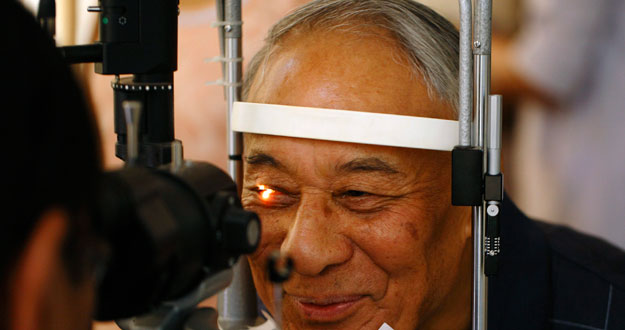 A man smiles as he receives his routine eye check-up after removing his cataracts in Kathmandu