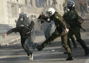 A protester tries to escape from riot policemen during a demonstration in Athens