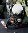 Agentes antidisturbios arrestan a un manifestante frente a la sede central de la polic&iacute;a en Atenas.