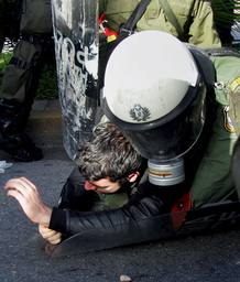 Agentes antidisturbios arrestan a un manifestante frente a la sede central de la polic&iacute;a en Atenas.